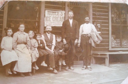 Julius seated with wife and children in front of store he ran